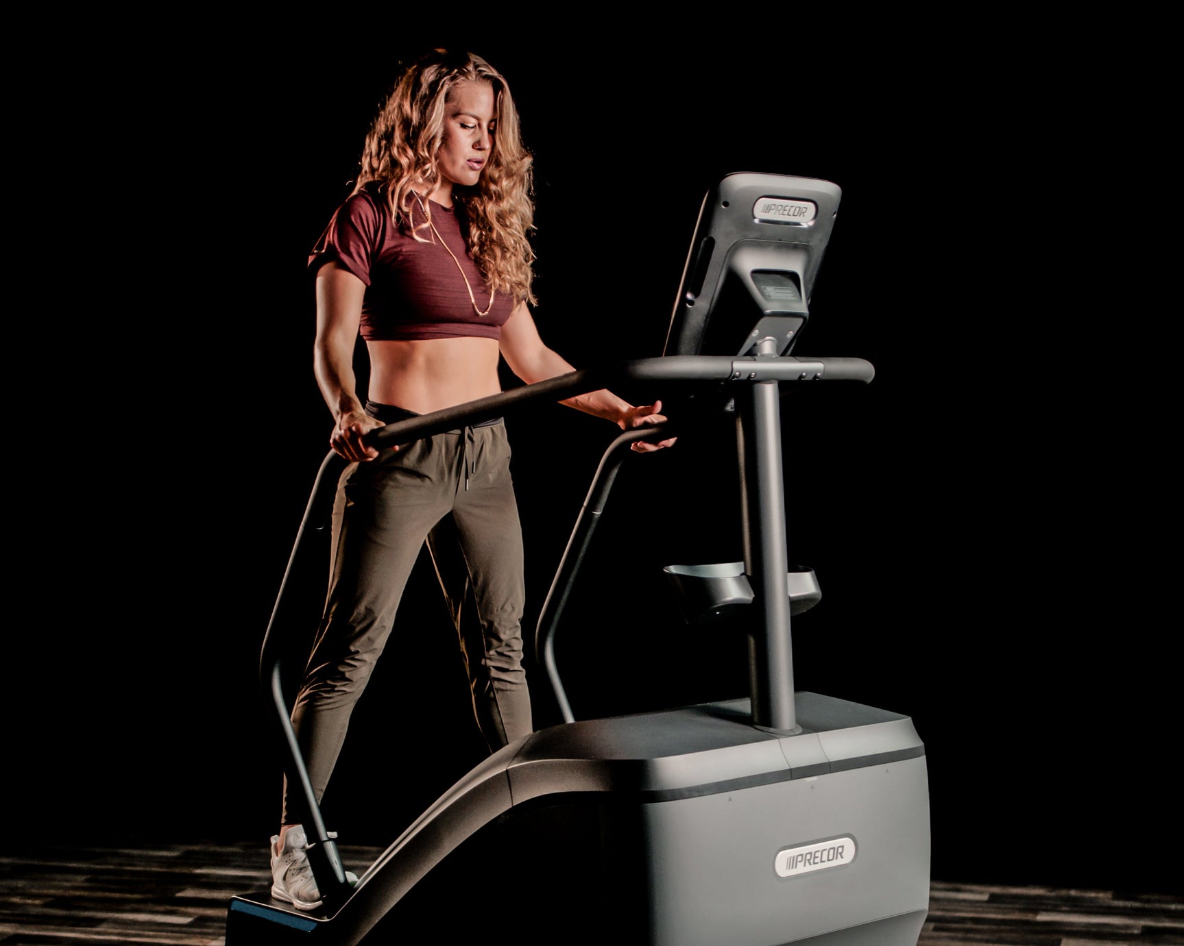 A woman using a precor exerciser from wellness first in a dark room