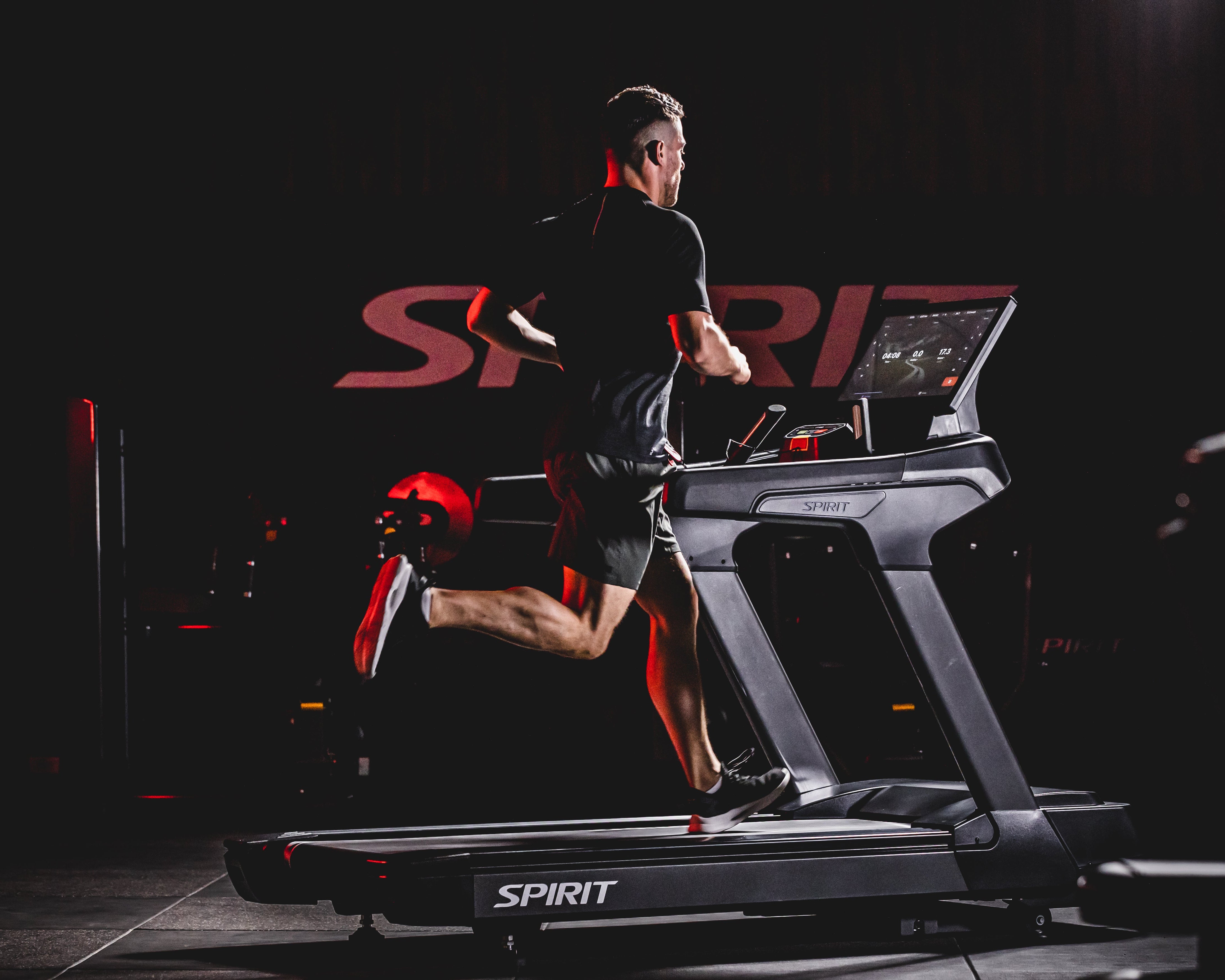 Person running on a treadmill branded 'Spirit' in a dark setting