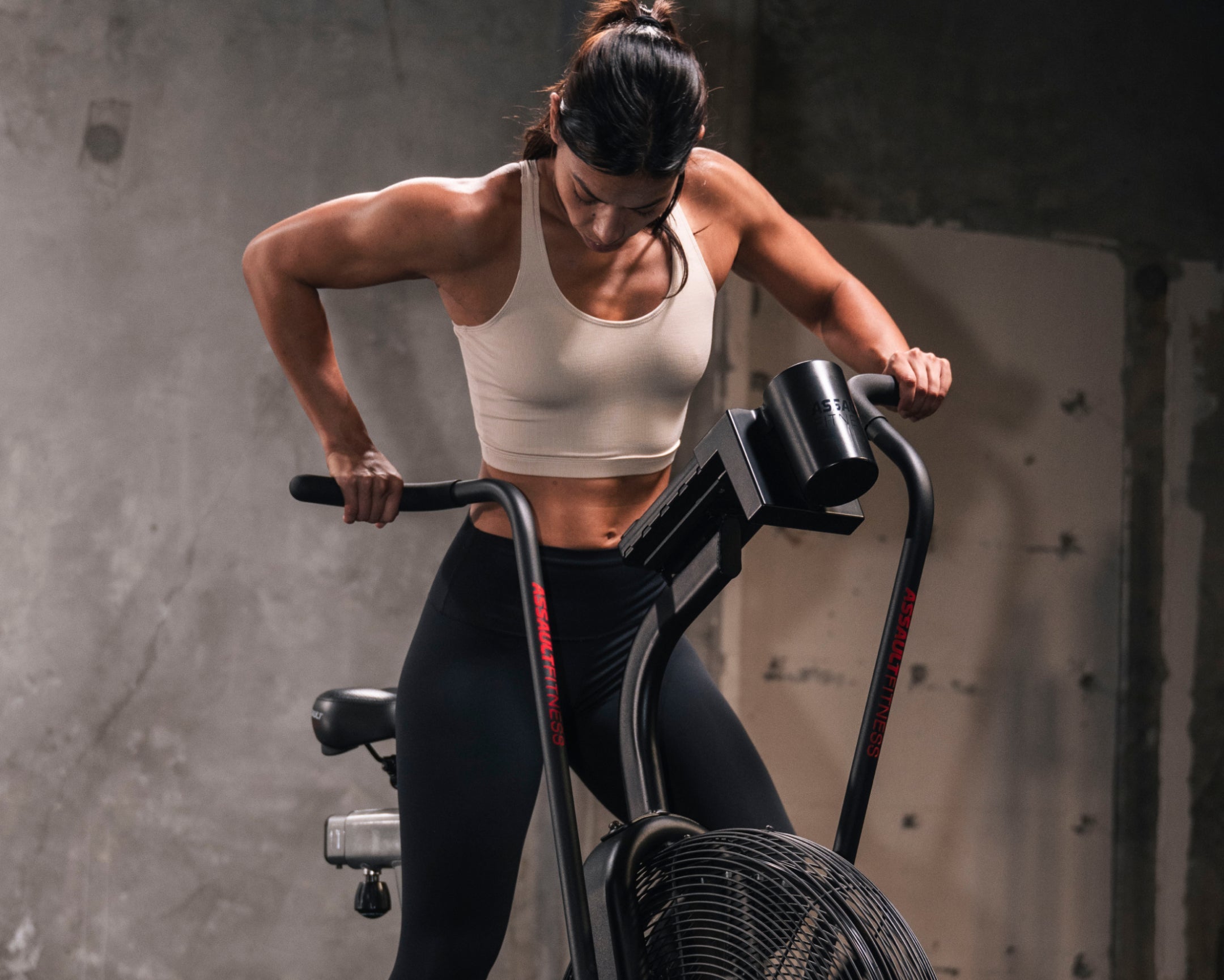 Woman exercising on  human powered assauot fitness bike in a gym setting