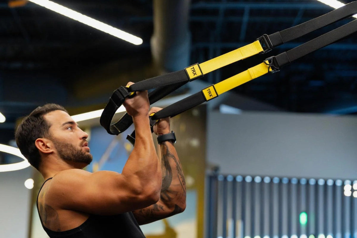 Man using TRX suspension straps in a gym setting